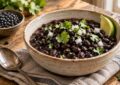 Bowl Of Cooked Black Beans With Cilantro, Chopped Onion And Lime