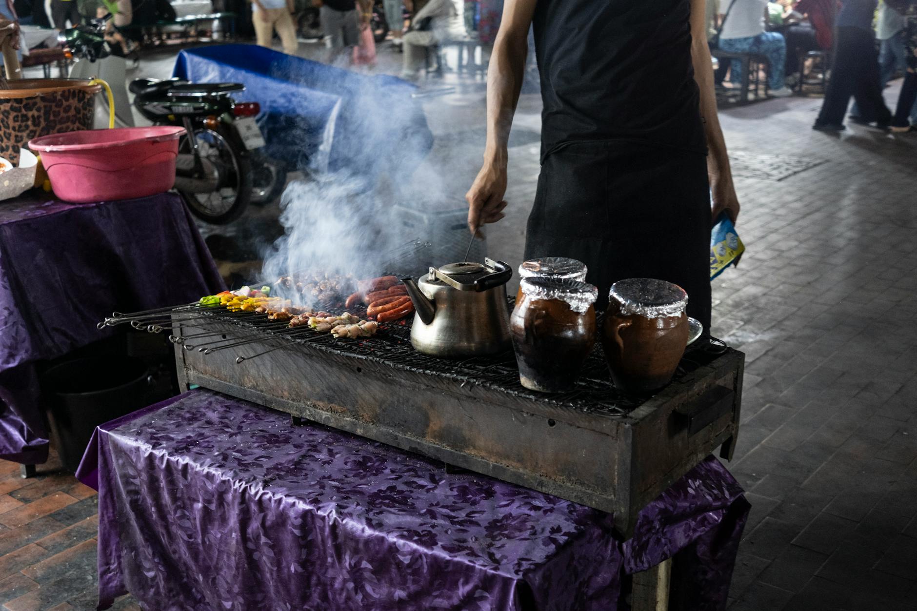 A Man Grilling Sausages On A Grill On A Street