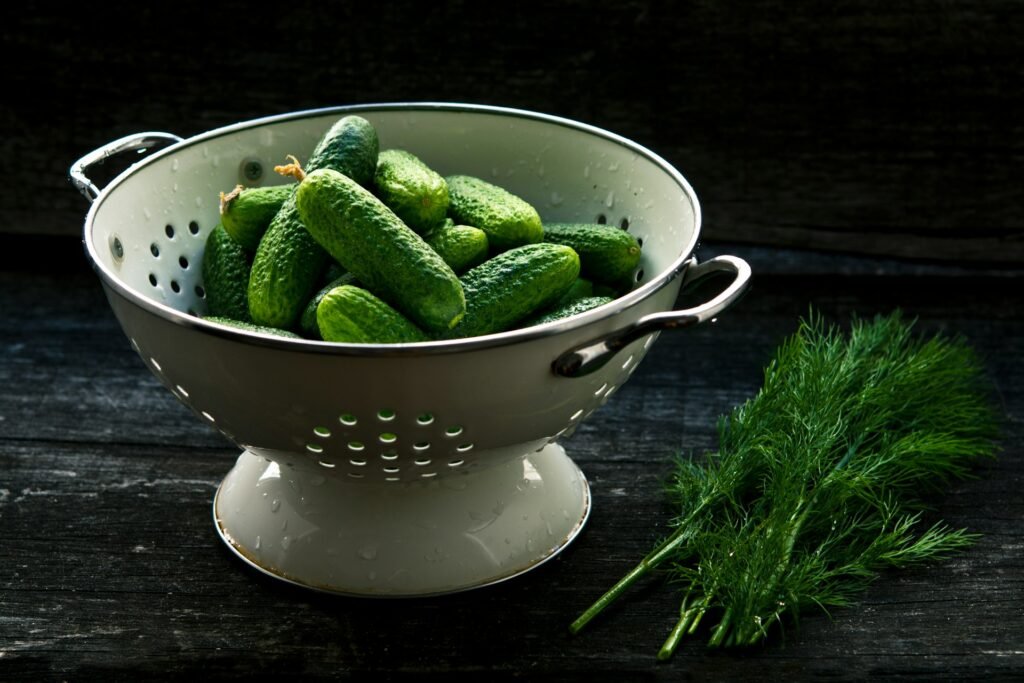 A Colander Full Of Cucumbers And A Bunch Of Dill