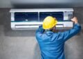 A Man Wearing A Hard Hat And Working On A Air Conditioner