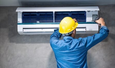 A Man Wearing A Hard Hat And Working On A Air Conditioner