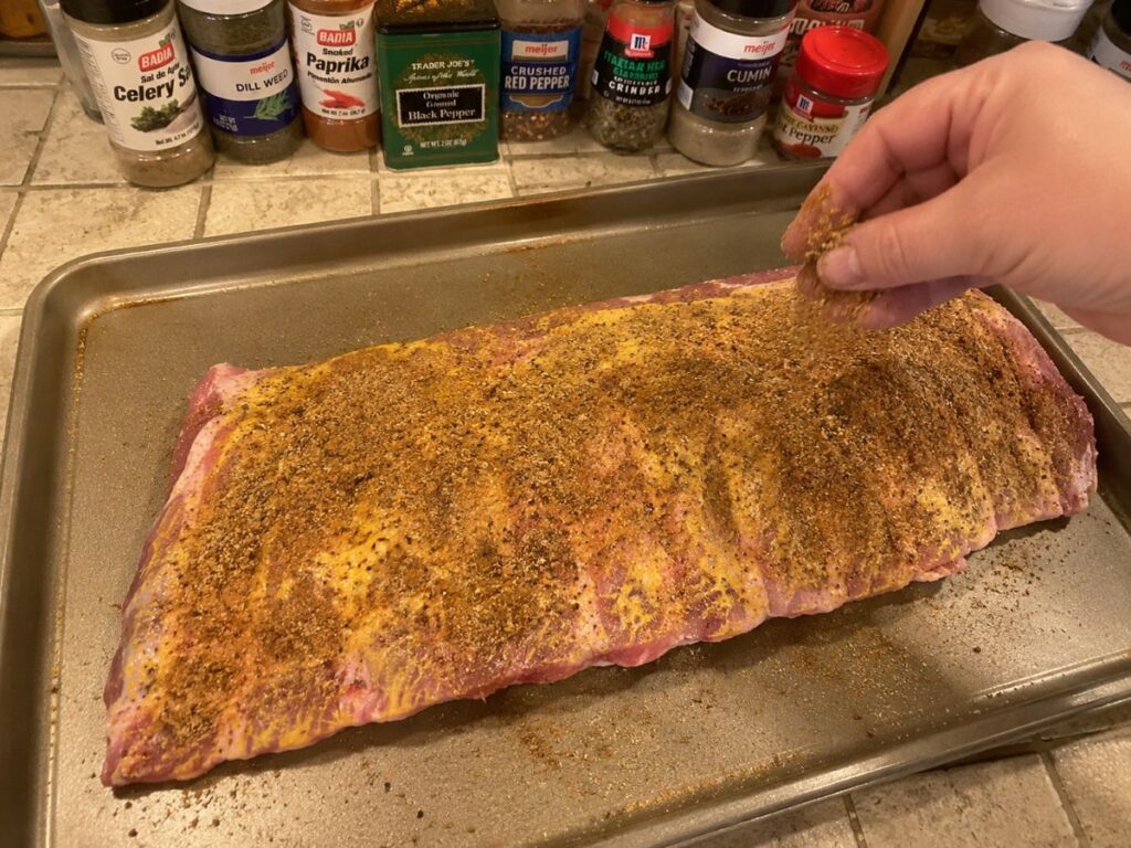 Pork Spare Ribs Being Seasoned With Mustard And Barbecue Dry Rub On A Sheet Pan.